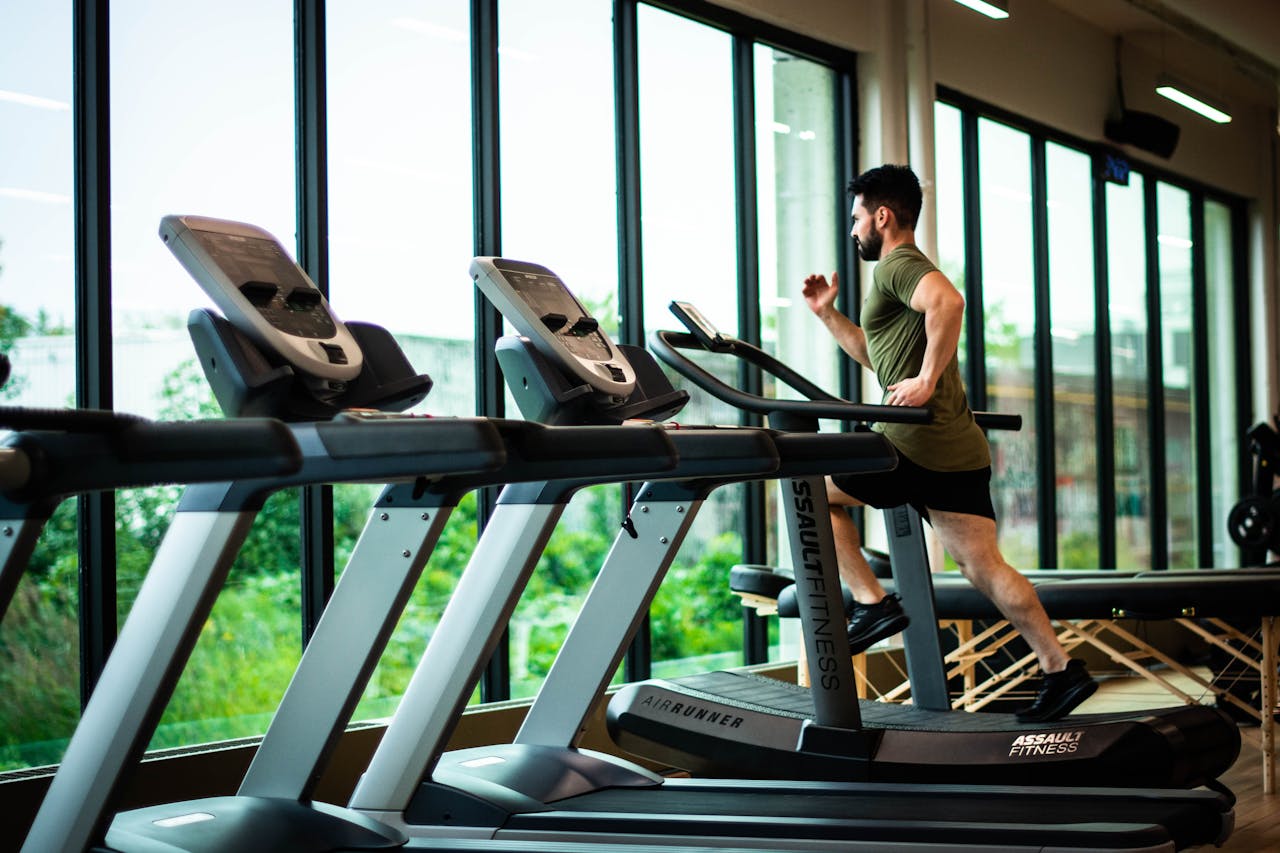Mastering the First Impression: Your intriguing post title goes here Young man workouts on treadmill in modern gym with large windows and natural light.