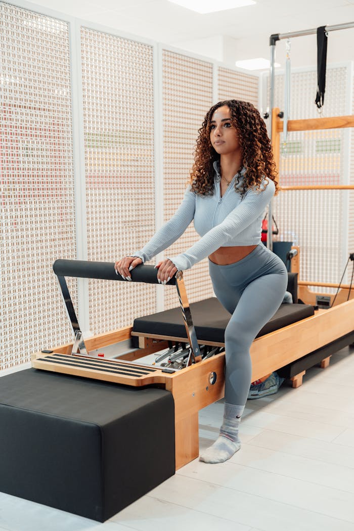 digital-01 Woman exercising on pilates reformer machine indoors. Focus on fitness and wellbeing.