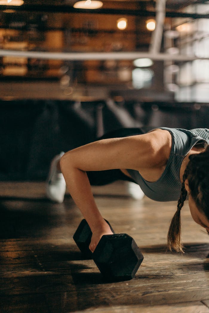 creative-03 Fit woman doing a dumbbell push-up in a gym, highlighting strength and fitness training.